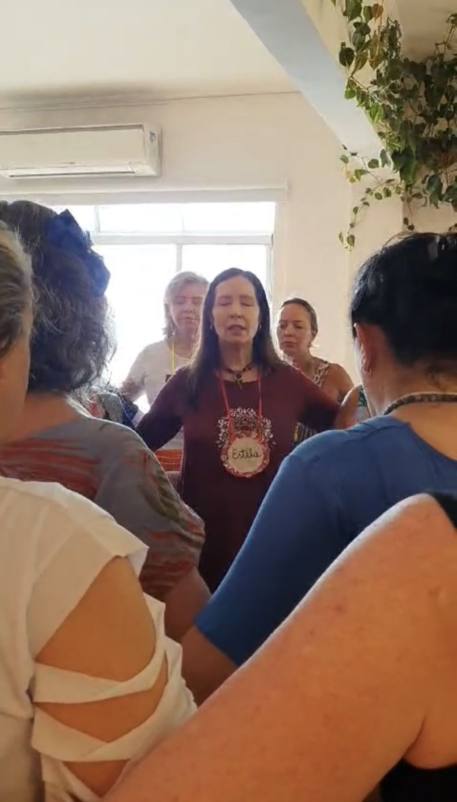Estela Gomes no centro da roda, entre participantes de mãos dadas