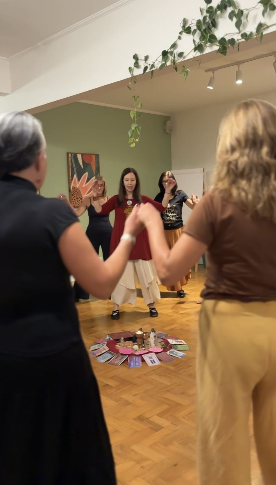 Mulheres de mãos dadas em roda em torno de uma mandala de cartas