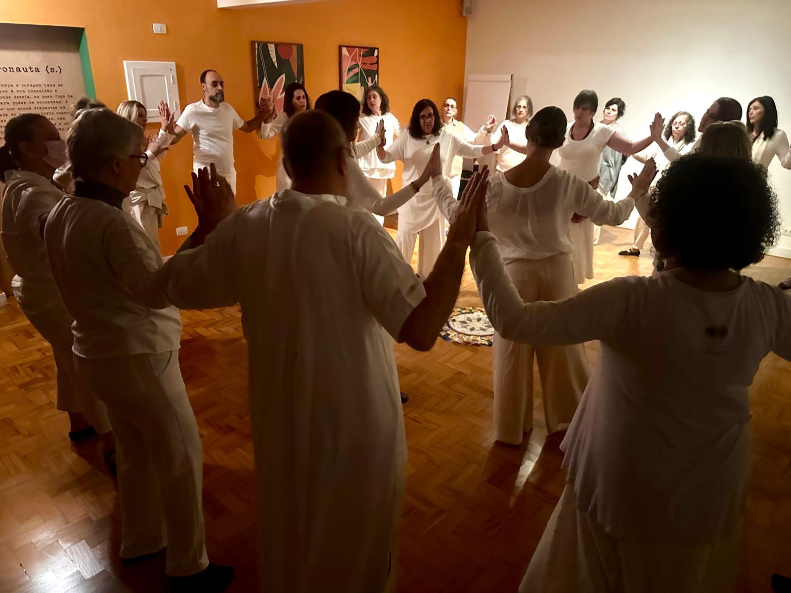 Roda meditativa: participantes vestidas de branco com os braços erguidos