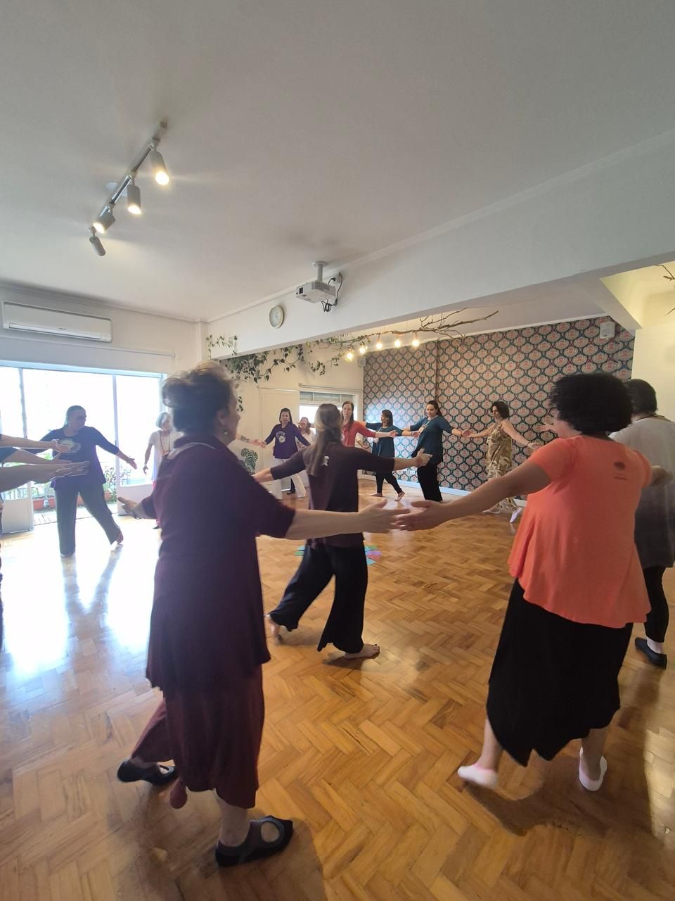 Roda de mulheres de mãos dadas dançando no salão